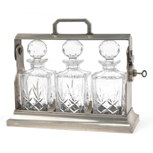 283 - Silver plated three bottle tantalus stand with three cut glass decanters and key, 34.5cm wide