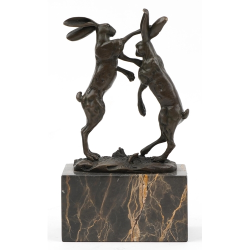 411 - Pair of patinated bronze boxing hares signed Nick, raised on a rectangular marble block base, 24cm h... 