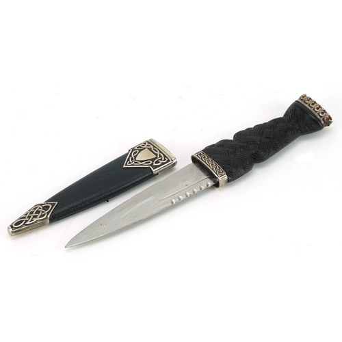 412 - Scottish sgian dubh with carved wood knot design handle, silver mounts and orange stone top, housed ... 