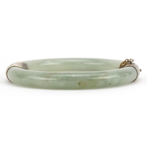 165 - Chinese green jade hinged bangle with silver gilt mounts, 7cm in diameter