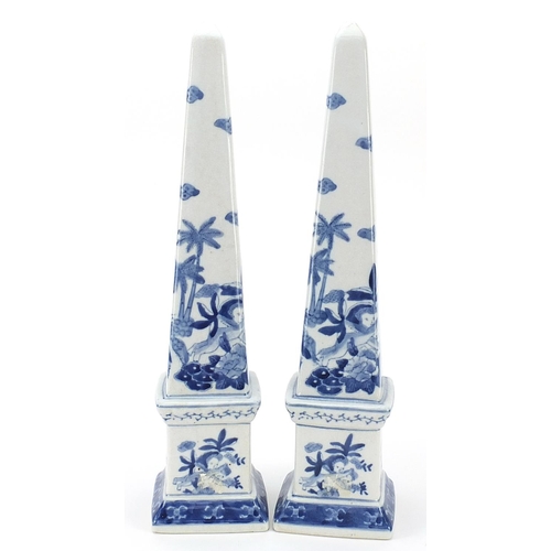 1345 - Pair of blue and white porcelain obelisks decorated with Putti amongst flowers, 41.5cm high