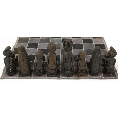 1438 - South African carved stone figural chess set with board, Rhodesia paper label to the base of the che... 