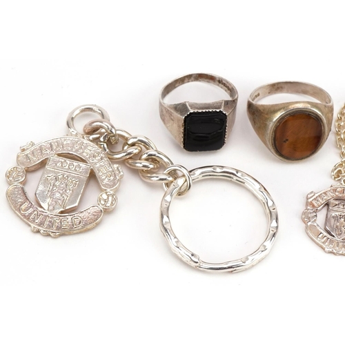 2363 - Two silver signet rings including one set with a tiger's eye, a white metal Manchester United keyrin... 