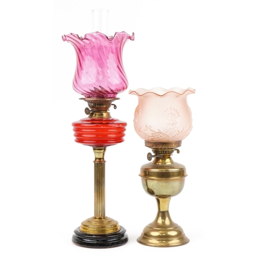 93 - Two Victorian brass oil lamps including an example with reeded column and cranberry glass shade, the... 