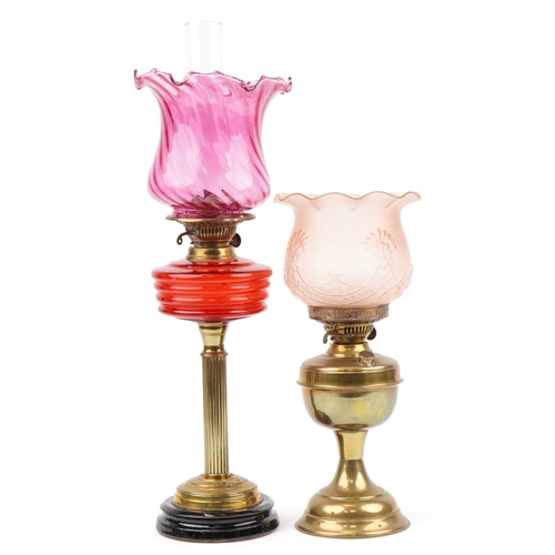 93 - Two Victorian brass oil lamps including an example with reeded column and cranberry glass shade, the... 