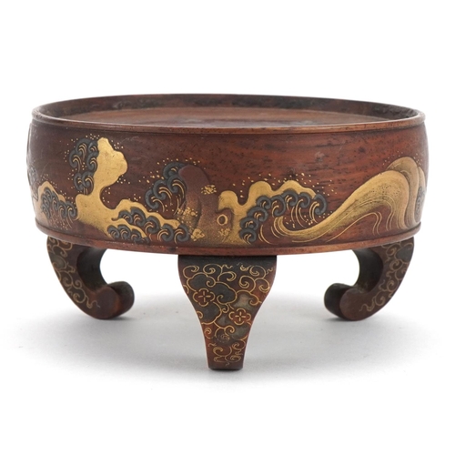 127 - Japanese hardwood three footed stand lacquered and gilded with crashing waves, 10.5cm in diameter