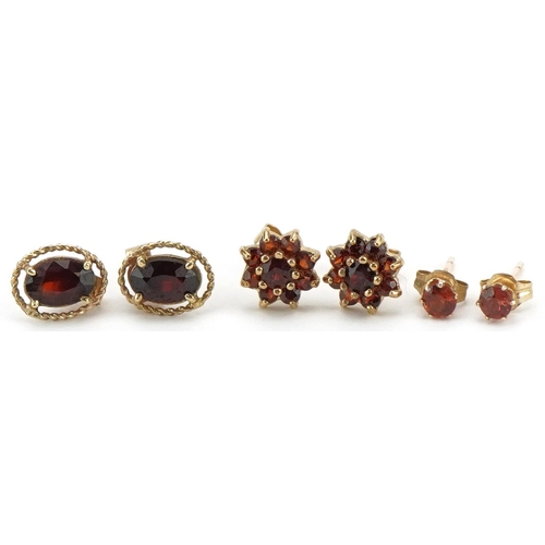 2192 - Three pairs of 9ct gold garnet earrings comprising solitaire studs and flower head clusters, the lar... 