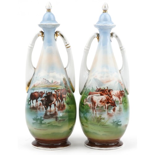 652 - Pair of continental porcelain vases and covers with twin handles decorated with cattle before mounta... 