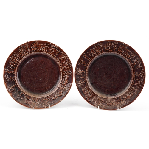 527 - Pair of T G Green treacle glazed plates decorated in relief with peasants, each 31cm in diameter