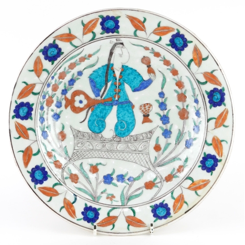31 - Turkish Ottoman Iznik plate hand painted with a figure and stylised flowers, 32cm in diameter