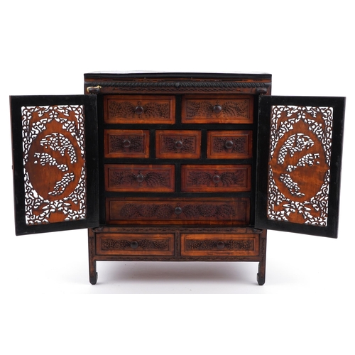 187 - Chinese table cabinet with pair of doors enclosing eight drawers, finely carved and pierced with fig... 