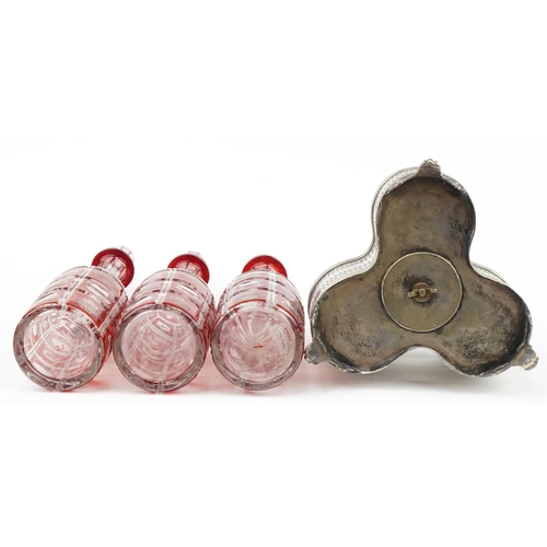 230 - 19th century silver plated three bottle tantalus housing three Bohemian ruby flashed cut glass decan... 