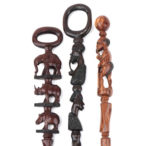 509 - Three African hardwood walking sticks including two carved with figures, the largest 104cm in length