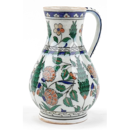 164 - Turkish Iznik pottery handled jug hand painted with stylised flowers, 25cm high