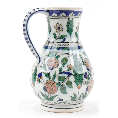 164 - Turkish Iznik pottery handled jug hand painted with stylised flowers, 25cm high