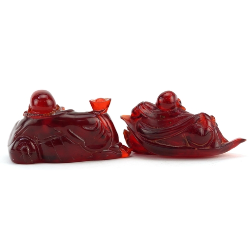 663 - Two Chinese cherry amber coloured Buddhas, the largest 15cm wide