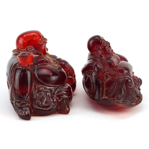 663 - Two Chinese cherry amber coloured Buddhas, the largest 15cm wide