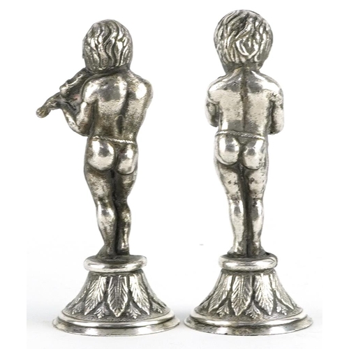 634 - Two continental white metal figures of semi nude male musicians, each 8.5cm high