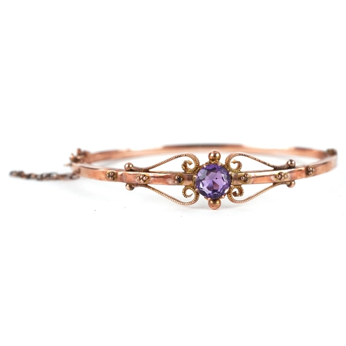 2028 - Edwardian 9ct rose gold amethyst bangle with scrolled decoration, the amethyst approximately 6.6mm i... 