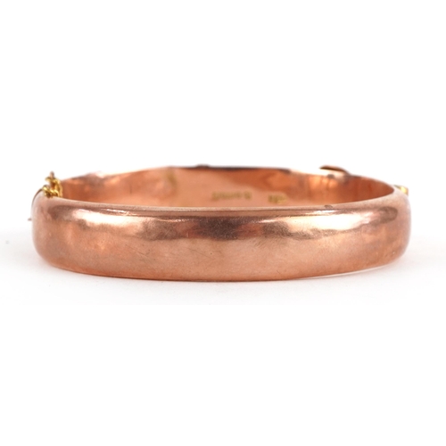 63 - Edwardian 9ct rose gold buckle design hinged bangle engraved with flowers and foliage, 6.5cm wide, 1... 