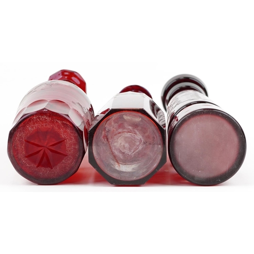 170 - Three Bohemian ruby glass decanters with stoppers including one etched with grapevines, the largest ... 