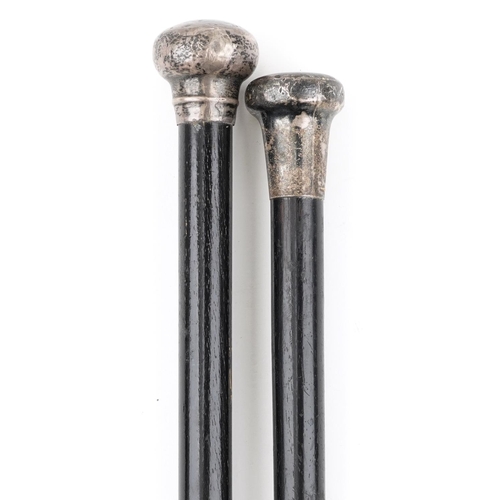 2359 - Two ebonised walking sticks with silver pommels, the largest 90cm in length