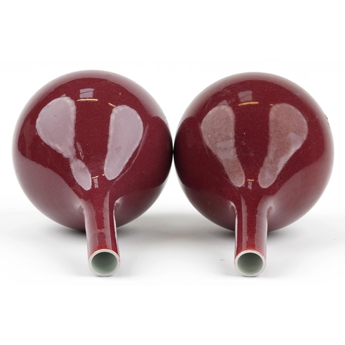 527 - Pair of Chinese porcelain long neck bottle vases having sang de boeuf glazes, each 34cm high