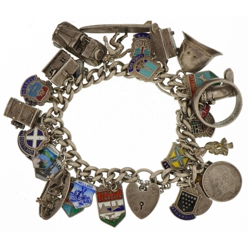 3233 - Heavy silver charm bracelet with a large selection of mostly silver charms, some opening, including ... 