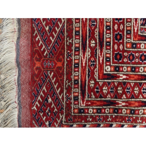 1030 - Rectangular Persian red ground rug having an allover repeat floral design, 190cm x 120cm