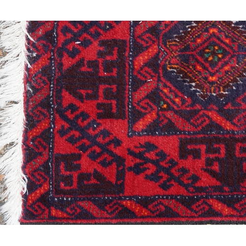 1015 - Rectangular Persian red ground rug having an allover repeat design within a geometric border, 190cm ... 