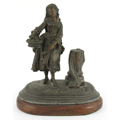 85 - 19th century spelter match sticker of a female holding a basket raised on an oval oak base, 19.5cm w... 