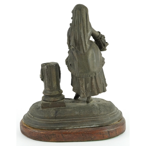 85 - 19th century spelter match sticker of a female holding a basket raised on an oval oak base, 19.5cm w... 