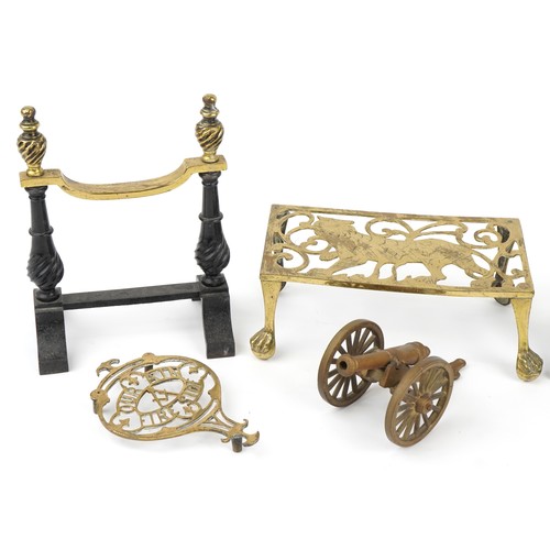 175 - Pair of Victorian brass and cast iron firedogs, lion trivet, small brass trivet and a brass cannon, ... 