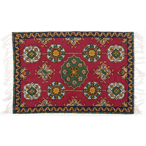 1537 - Rectangular Moroccan rug having an all over repeat flower head design onto a red ground, 88cm x 57cm