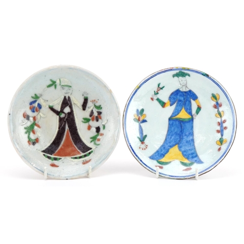 489 - Two Iznik pottery shallow dishes hand painted with figures wearing traditional dress, the largest 14... 