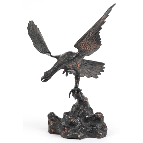 1697 - Bronzed cast metal study of an eagle perched on a rock, 44cm high