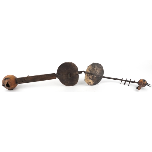 1659 - Two tribal interest African wooden animal hide musical instruments, the largest 68.5cm in length