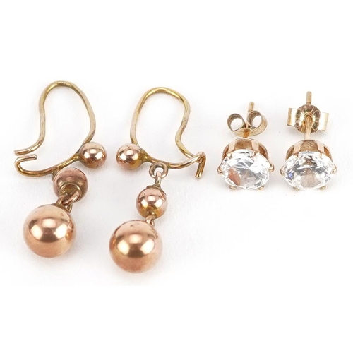 2164 - Two pairs of yellow metal earrings comprising clear stone studs and graduated ball drops, the larges... 