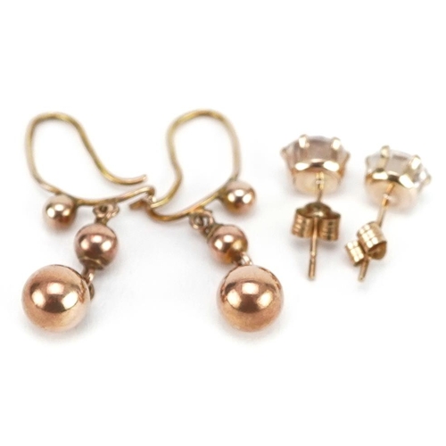 2164 - Two pairs of yellow metal earrings comprising clear stone studs and graduated ball drops, the larges... 