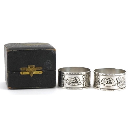 1507 - Pair of Victorian Aeshetic silver napkin rings cast with flowers and foliage housed in a fitted case... 