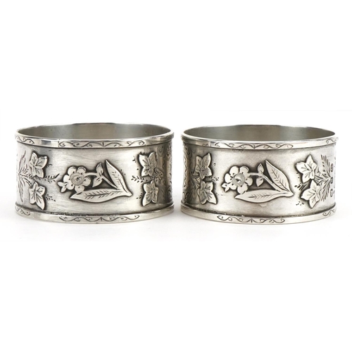 1507 - Pair of Victorian Aeshetic silver napkin rings cast with flowers and foliage housed in a fitted case... 