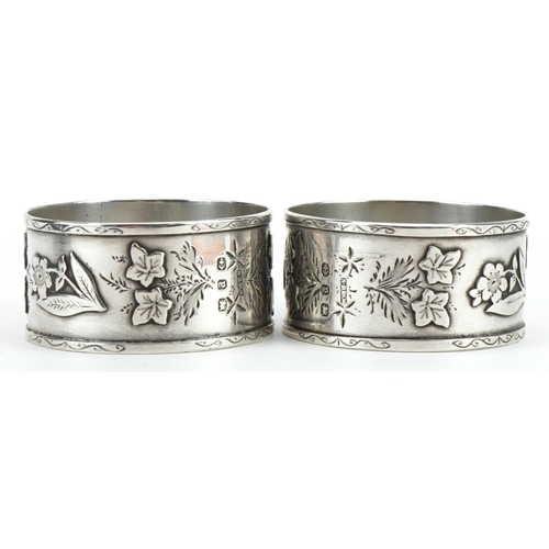 1507 - Pair of Victorian Aeshetic silver napkin rings cast with flowers and foliage housed in a fitted case... 