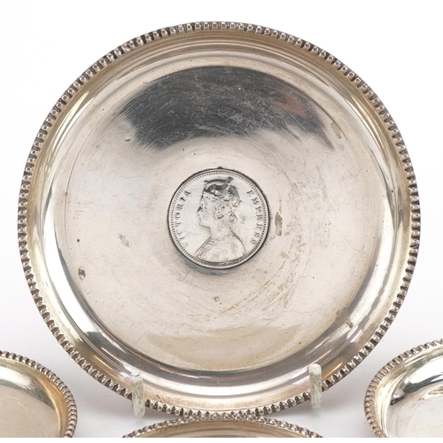 196 - Four 19th century Indian silver dishes, each inset with a rupee, comprising dates 1862, 1878, 1878 a... 