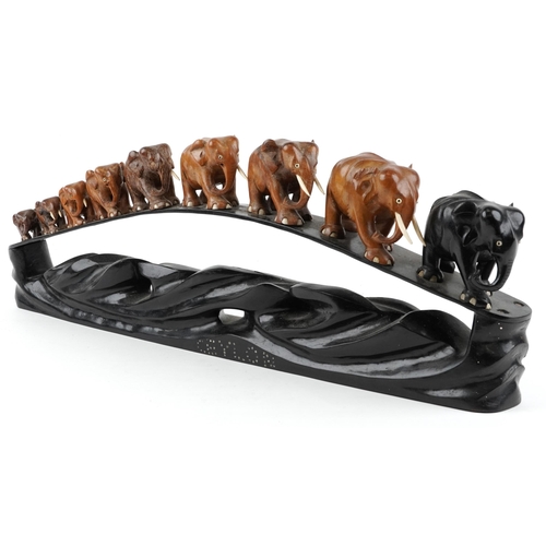 1730 - African ebony stand surmounted with nine graduated hardwood elephants entitled Ceylon, 78cm in lengt... 