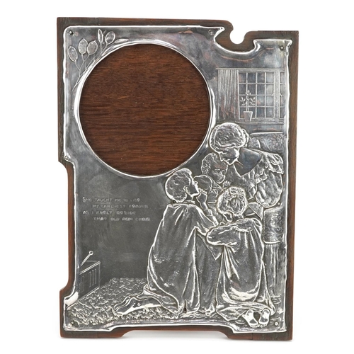 122 - Art Nouveau unmarked silver easel photo frame embossed with a family praying, She taught me to lisp,... 