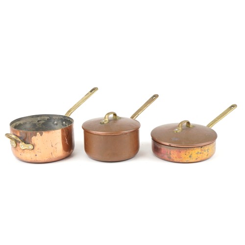 1673 - Three Victorian copper and brass saucepans housed in a tapering wrought cast iron rack