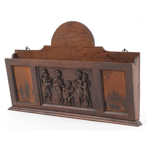 444 - Early 20th century oak letter rack carved with Putti musicians, 46cm wide