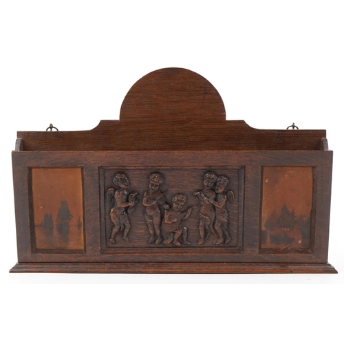 444 - Early 20th century oak letter rack carved with Putti musicians, 46cm wide