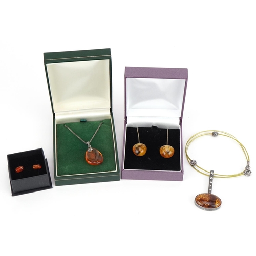 2582 - Silver mounted amber jewellery comprising two pendants on chains and two pairs of earrings