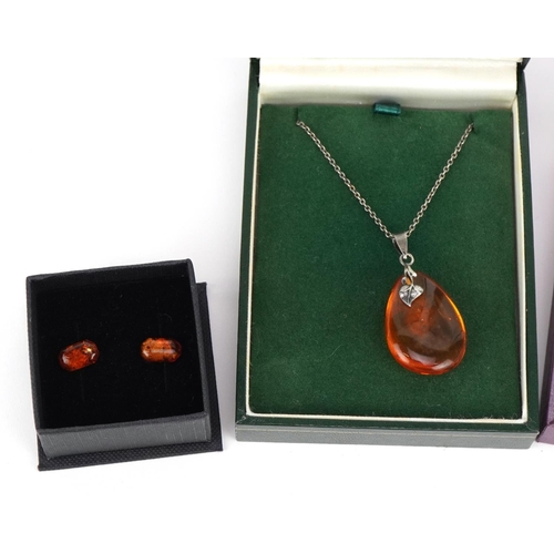 2582 - Silver mounted amber jewellery comprising two pendants on chains and two pairs of earrings